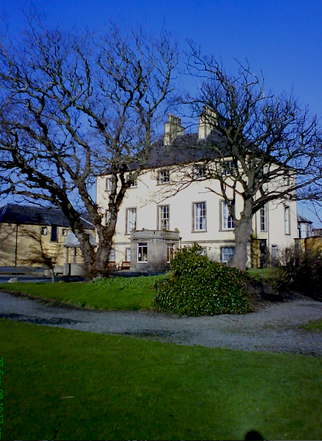 White-harled mansion of Banff Castle seen across its lawn, with a central entrance, hipped roof and dormer windows