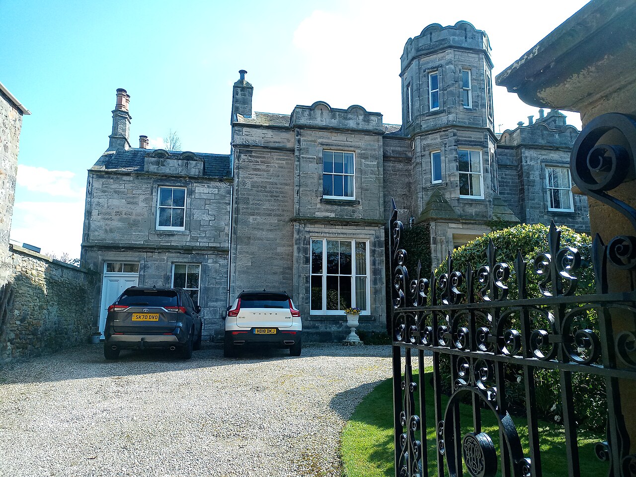 The harled stables at The Lodge in Aberlady, with stone dressings, a central gable and slated roofs.