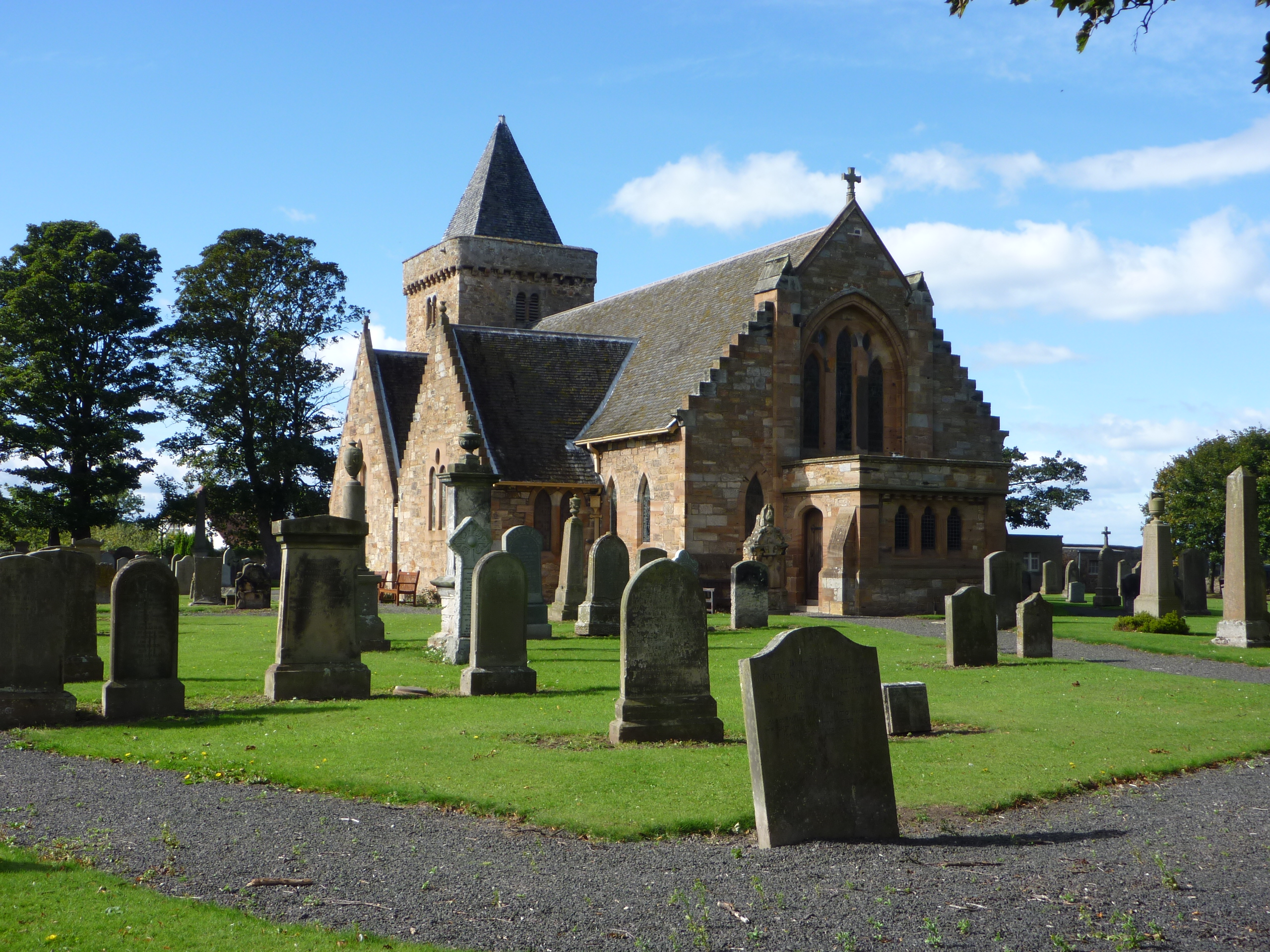 The east end of Aberlady Parish Church, with its stone gable and traceried window seen beyond the graveyard wall.