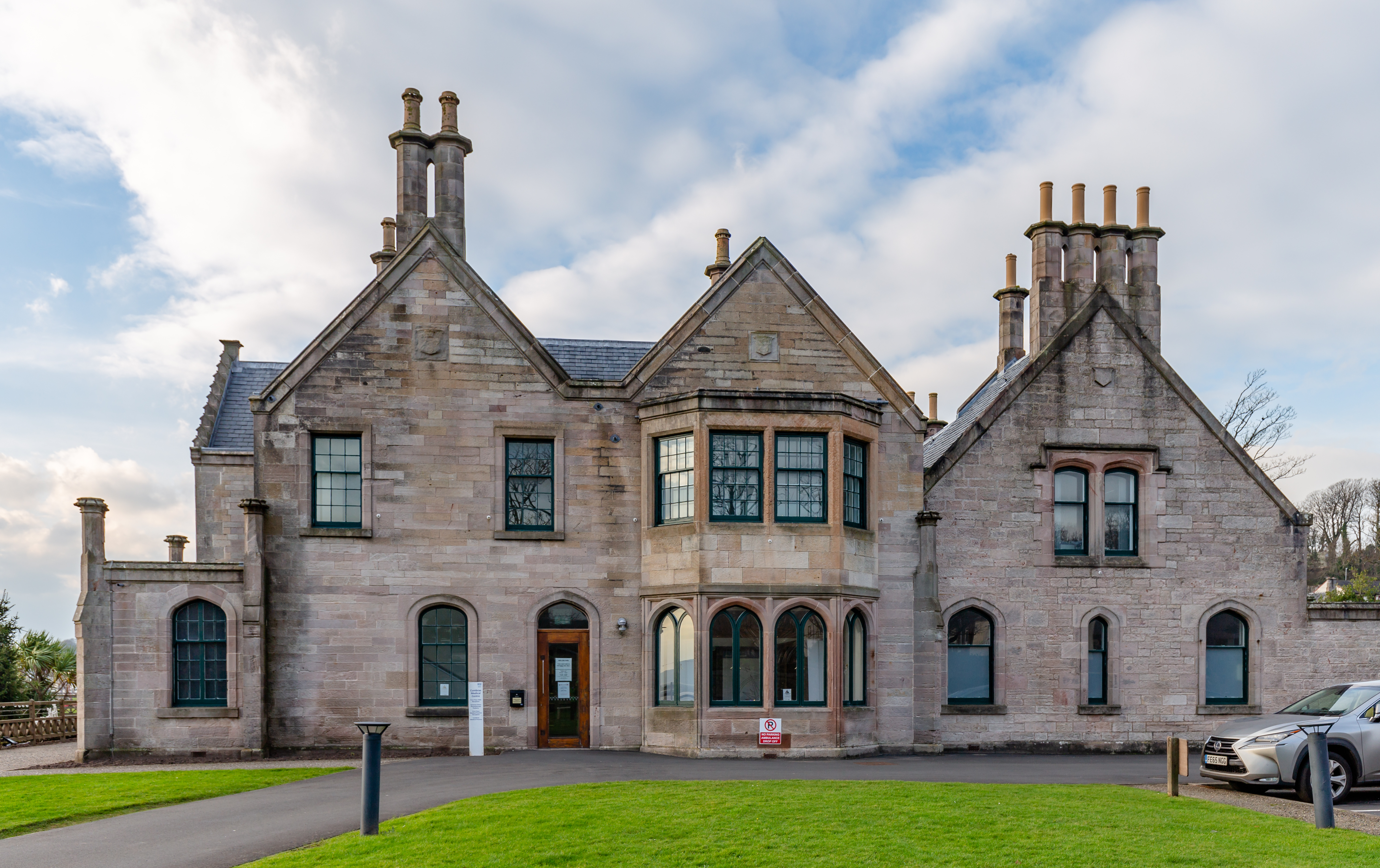 Garrison House in Millport, with stone gables, tall chimneys and a projecting bay facing a lawn.