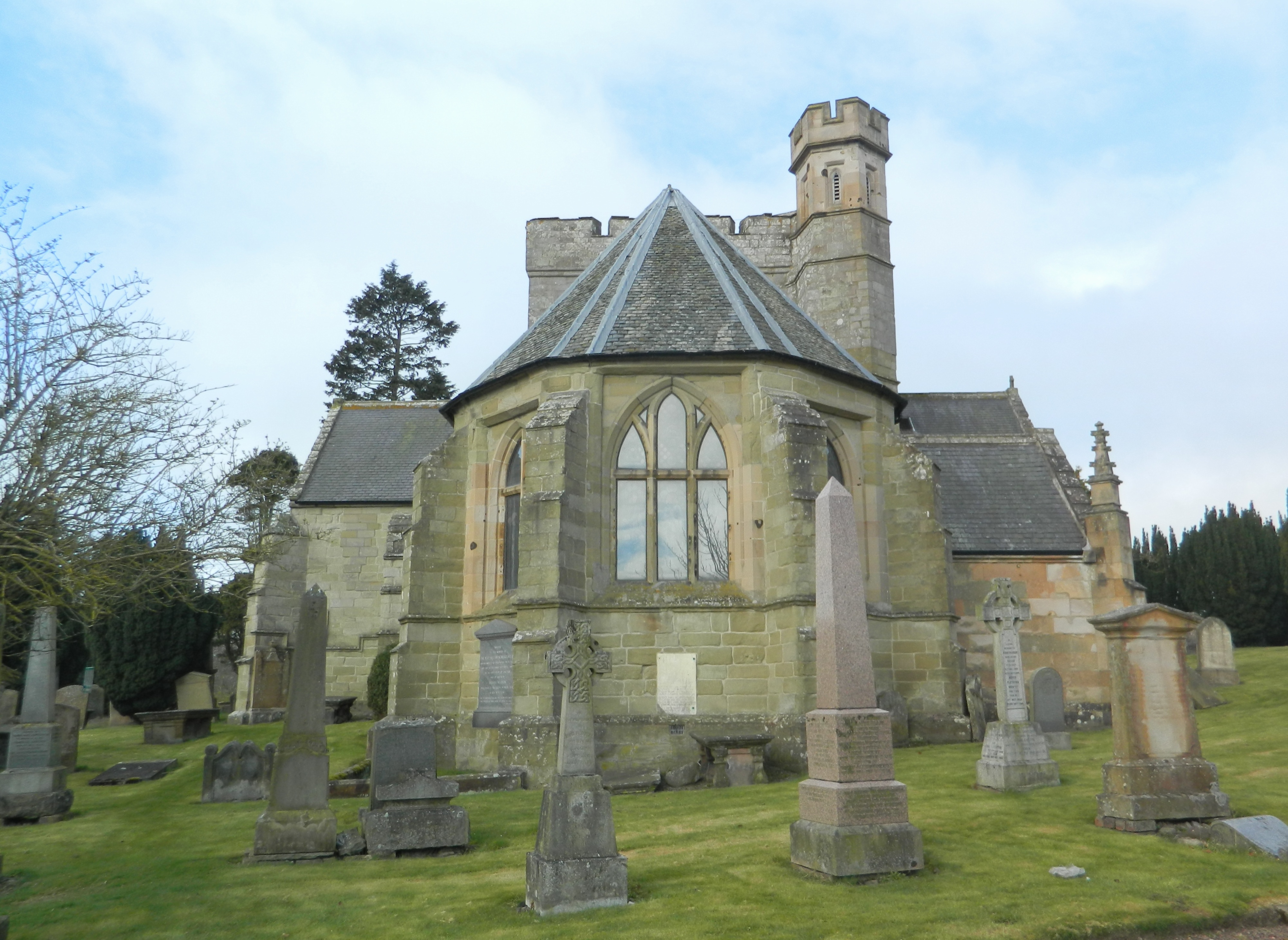 Biggar Kirk's long stone nave, crow-stepped gables and buttressed east end seen across the churchyard.