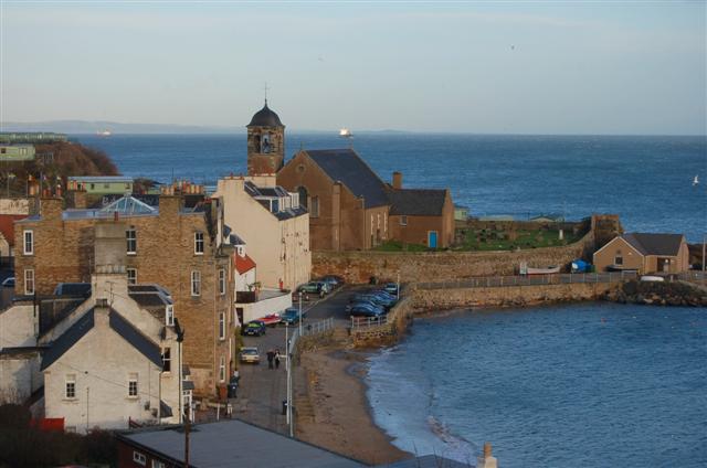 Kinghorn Parish Church of St Leonard rising above the harbour-side roofs.