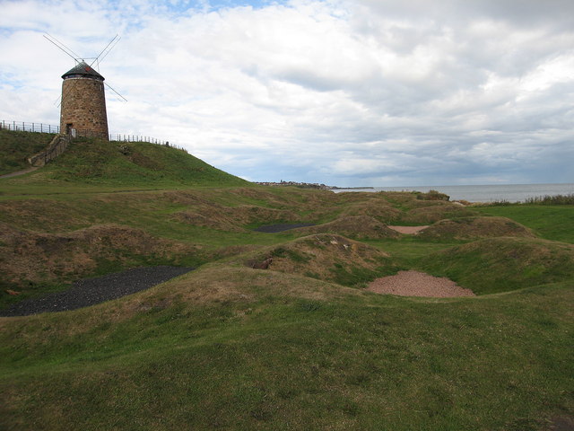 The circular St Monans windmill tower beyond the low stone remains of the saltpan houses.