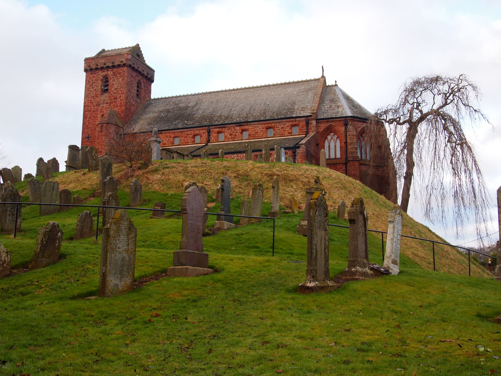 St Vigeans Parish Kirk on its raised churchyard site, with the stone nave and tower seen beyond the graves.